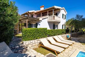 ein Haus mit 2 Liegestühlen und einem Pool in der Unterkunft Villas Rab Palit in Rab