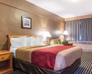 um quarto de hotel com uma cama grande e uma cadeira em Econo Lodge Downtown Ottawa em Ottawa