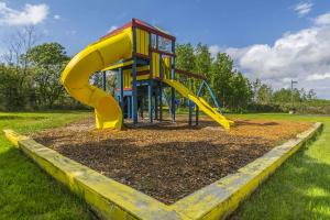 a playground with a yellow slide in a park at Quality Inn in Rivière-du-Loup