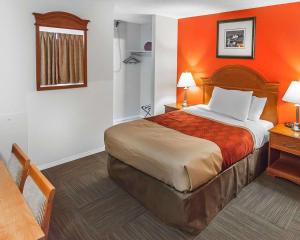 a hotel room with a bed with an orange wall at Econo Lodge Inn & Suites Drumheller in Drumheller