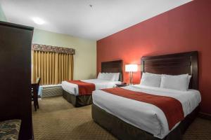 Comfort Inn & Suites Airport South في كالغاري: سريرين في غرفة الفندق بجدران حمراء