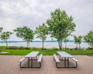 two picnic tables and benches in front of the water at Hotel Quality Suites in Sainte-Anne-de-Beaupré