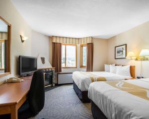 a hotel room with two beds and a desk at Quality Resort Chateau Canmore in Canmore