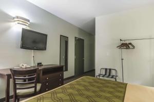 een slaapkamer met een bed, een bureau en een televisie bij Econolodge Huntsville in Huntsville