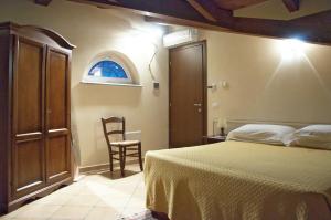 a bedroom with a bed and a chair and a window at Hotel Ristorante La Torretta in Bianzè