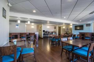 Comfort Inn & Suites Airport South في كالغاري: غرفة طعام مع طاولات خشبية وكراسي زرقاء