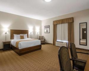 Quality Inn & Suites في Estevan: غرفه فندقيه بسرير وكرسي