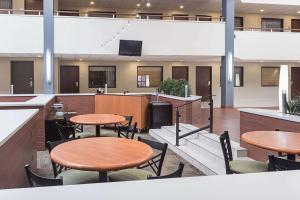 a cafeteria with tables and chairs and a tv at Quality Suites in Lansing