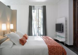 a bedroom with a large white bed and a television at Hospes Puerta de Alcalá, a Member of Design Hotels in Madrid