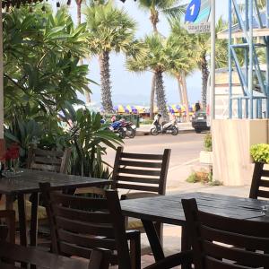 una mesa y sillas en un restaurante con palmeras en Sunlight Hotel en Jomtien Beach