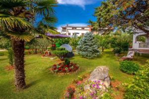 ein Garten mit einer Palme und Blumen in der Unterkunft Garden paradise App in Sveti Vid-Miholjice