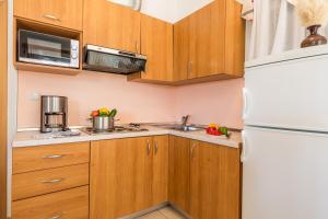 a kitchen with wooden cabinets and a white refrigerator at Villas Rab Palit in Rab
