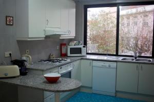 a kitchen with white cabinets and a microwave and a counter at Casino Figueira Prime Apartment in Figueira da Foz