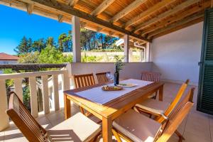 a wooden table and chairs on the balcony of a house at Villas Rab Palit in Rab