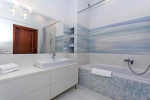W łazience znajduje się umywalka, wanna i lustro. w obiekcie Mumbai - Neptun Park by OneApartments w Gdańsku