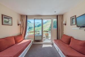 a living room with two red couches and a large window at Residence Le Sepia - maeva Home in Avoriaz