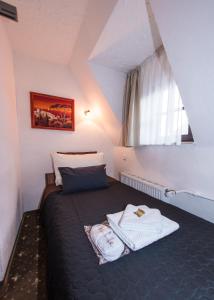 a small bedroom with a bed with a window at Hotel und Restaurant Löwenbräu Köln in Cologne