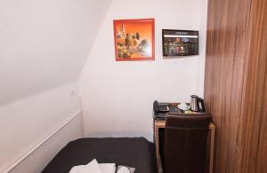 a room with a bed and a desk with a phone at Hotel und Restaurant Löwenbräu Köln in Cologne