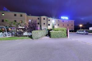 a hotel at night with a car parked in a parking lot at Hotel Le Saint Vincent Lyon Sud in Vourles