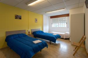 sypialnia z 2 niebieskimi łóżkami w pokoju w obiekcie A taberna de vento w mieście Lalín