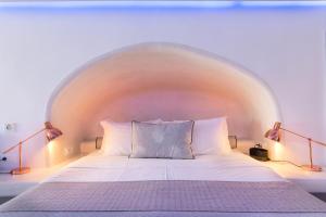 a white bed with two pillows in a room at Secret Legend Suites in Oia