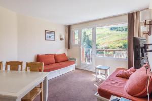 een woonkamer met een rode bank en een raam bij Residence Le Sepia - maeva Home in Avoriaz