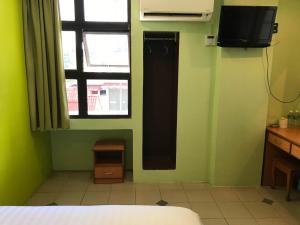 a bedroom with a green wall with a window and a television at Hotel dan Restoran Seri Kangsar in Kuala Kangsar