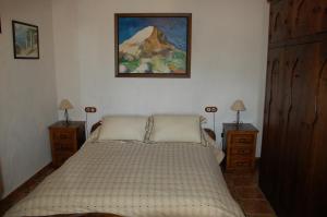 Un dormitorio con una cama con dos mesitas de noche y un cuadro en la pared. en Cortijo Lagarín, en El Gastor 76 fotos más