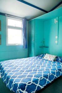 1 dormitorio azul con 1 cama grande y ventana en Camping Os Fieitás en O Grove