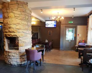 a restaurant with a stone fireplace and tables and chairs at Corriegarth Hotel in Inverness