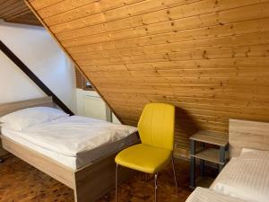 a bedroom with a bed and a yellow chair at AB Apartment Objekt 122 in Uhingen