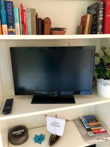 a computer monitor on a shelf with books at Annex bedroom-Oporto Garden in Porto