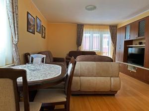 ein Wohnzimmer mit einem Tisch, einem Sofa und einem TV in der Unterkunft Apartments Nella in Kolašin