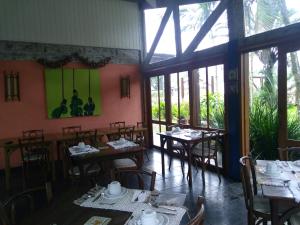 a dining room with tables and chairs and windows at Pousada das Maritacas in Ilhabela
