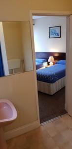a bathroom with a mirror and a bed and a sink at Hotel Avano - Pleasure Beach in Blackpool