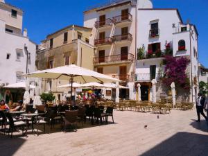 een patio met tafels, stoelen en parasols bij Casa Linda Sperlongaresort in Sperlonga