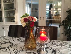 a vase with flowers and a candle on a table at B&B nancy in holland met eigen badkamer , Jacuzzi niet inclusief , independent bathroom jacuzzi not included in Aalten