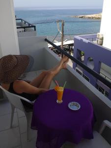 a woman sitting on a balcony with a drink on a table at Klery Studios in Hersonissos