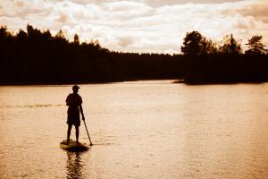 a person standing on a paddle board in the water at Lepaan Kartanon Vierashuone in Lepaa