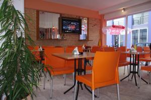 un comedor con mesas y sillas naranjas en un restaurante en Klery Studios, en Hersonissos
