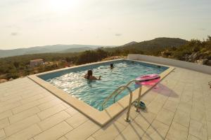 a woman in a swimming pool with mountains in the background at B&B On The Rocks in Blizna Donja