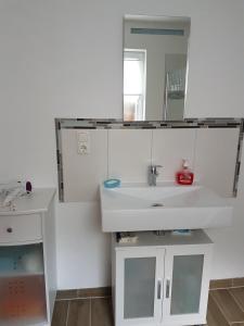 a white bathroom with a sink and a mirror at Luba in Hillesheim