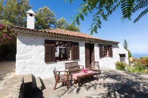 Casa blanca pequeña con mesa y sillas en Finca La Hondura, en La Orotava