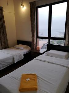 ein Hotelzimmer mit zwei Betten und einem Fenster in der Unterkunft Kota Kinabalu Marina Homestay in Kota Kinabalu