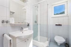 a white bathroom with a sink and a shower at Villas Rab Palit in Rab
