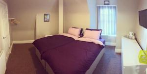 a bedroom with a bed with purple sheets and a window at Micklegate House in Selby