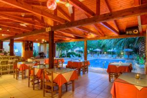 a restaurant with tables and chairs and a swimming pool at Sunrise Hotel & Apartments in Rodakino