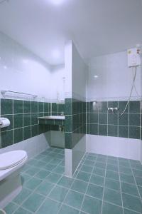 ein grün-weißes Bad mit einem WC und einer Dusche in der Unterkunft Green Island Guesthouse in Karon Beach