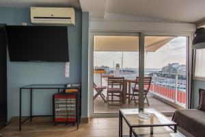 ein Wohnzimmer mit Balkon, Tisch und Stühlen in der Unterkunft Piraeus Apartment with Endless View in Piräus