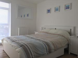 a white bedroom with a bed and a window at 23 Seagate Court in East Wittering